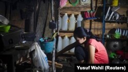 Seorang gadis yang menikah di bawah umur pada Maret 2020, sedang memasak di dapur rumahnya di Botteng Utara di Mamuju, Sulawesi Barat, pada 24 Juli 2020. (Foto: AFP/Yusuf Wahil)