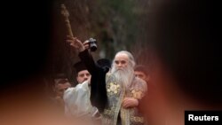 Arhiva - Mitropolit Amfilohije Radović, među vernicima, baca drveni krst u reku Ribnicu tokom proslave Bogojavljanja, u Podgorici, 19. januara 2013. (Rojters)