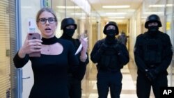 FILE - Opposition activist Lyubov Sobol reports live by phone as policemen stand guard during a raid at offices of the Anti-Corruption Foundation, in Moscow, Russia, Dec. 26, 2019. The foundation was established by prominent Kremlin critic Alexei Navalny.