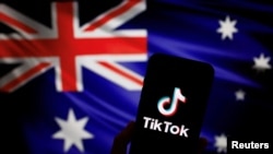 Logo aplikasi video TikTok milik China terlihat di smartphone di depan gambar bendera nasional Australia, 4 April 2023. Australia pmengatakan akan melarang TikTok di perangkat milik pemerintah. (Foto: REUTERS/Tingshu Wang)