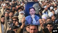 Seorang pendukung mantan PM Imran Khan yang dipenjara, memegang posternya selama pertemuan partai Pakistan Tehreek-e-Insaf (PTI) untuk memperingati "Hari Martir" guna menghormati mereka yang diduga tewas selama aksi protes bulan lalu, di Peshawar 15 Desember 2024. 