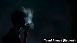 Seorang pekerja merokok saat berada di pabrik pengolahan tembakau di Makassar, Sulawesi Selatan, 29 Mei 2009. (Foto: REUTERS/Yusuf Ahmad)