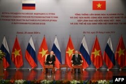 Presiden Rusia Vladimir Putin (kiri) dan Presiden Vietnam To Lam (kanan) mengikuti acara yang dihadiri oleh Asosiasi Persahabatan Vietnam dan generasi alumni Vietnam yang belajar di Rusia di Hanoi Opera House di Hanoi, 20 Juni 2024. (Manan VATSYAYANA / POOL / AFP)