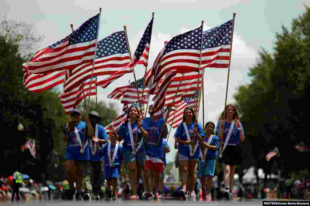 人们举着美国国旗参加华盛顿的独立日庆祝游行。(2019年7月4日)