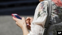 FILE - In this April 8, 2019, photo, a woman browses her smartphone. For many journalists working in Myanmar, the smartphone is a lifeline.