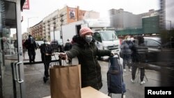 Žena u Njujorku uzima besplatan obrok, 18. april 2020. (Foto: Rojters/Jeenah Moon)