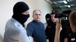 FILE - Paul Whelan, a former U.S. Marine, second left, who was arrested for alleged spying in Moscow at the end of 2018, is escorted by Federal Security Service officers to a court room in Moscow, Russia, Aug. 23, 2019.