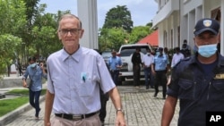 Seorang petugas polisi mengawal Richard Daschbach, tengah, seorang mantan misionaris dari Pennsylvania, A.S. pada saat kedatangannya untuk diadili di gedung pengadilan di Oecusse, Timor Leste. (Foto: AP)