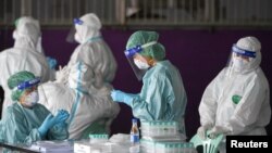 Para petugas medis mengumpulkan sampel hasil tes swab COVID-19 para pekerja migran di tengah perebakan pandemi di provinsi Samut Sakhon, Thailand (foto: dok). 