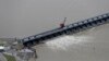 FILE - Workers open the gates of the Bonnet Carre spillway, a river diversion structure, which diverts water from the rising Mississippi River, left, to Lake Pontchartrain, in Norco, La., March 8, 2018.