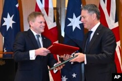 Menteri Pertahanan Inggris Grant Shapps (kiri), dan Menteri Pertahanan Australia Richard Marles bertukar perjanjian kerja sama pertahanan dan keamanan baru di Gedung Parlemen di Gedung Parlemen di Canberra, Kamis, 21 Maret 2024. (Lukas Coch/AAP Image via AP)