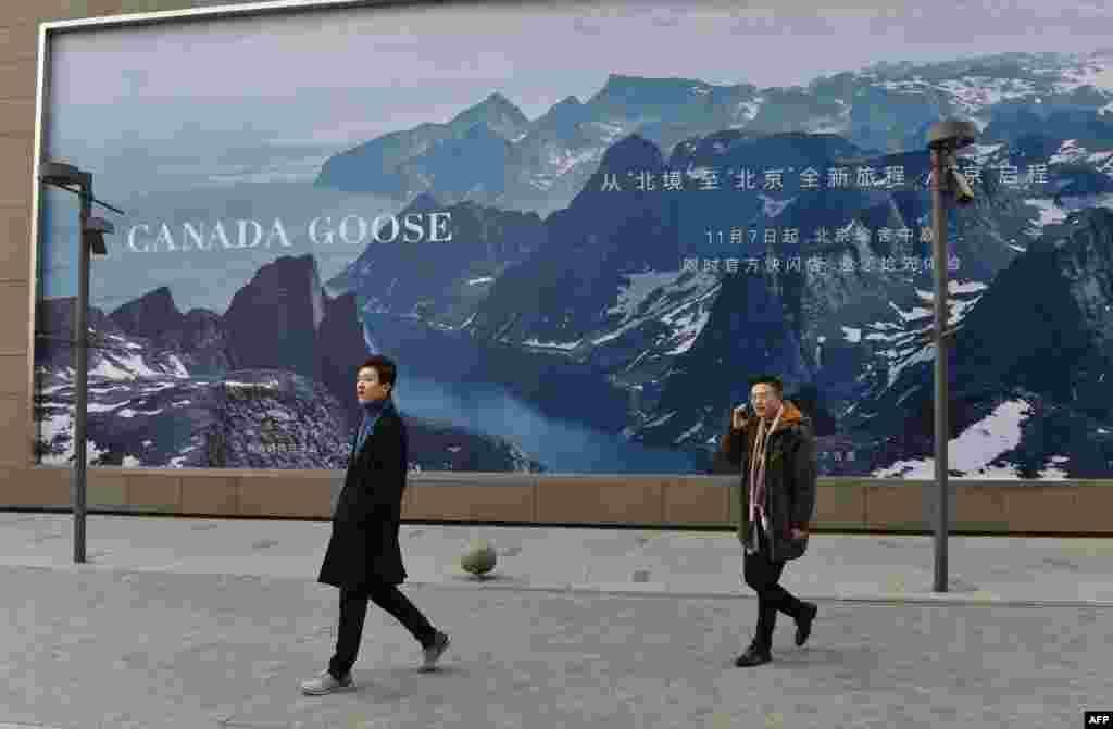 2018年12月15日,两名男子走过北京的“加拿大鹅”新店附近的广告牌。华为财务官孟晚舟12月在加拿大被捕后,中国逮捕了两名加拿大公民,中加关系紧张。加拿大鹅在北京首家商店的开张时间推迟了两周,但加拿大鹅表示推迟原因是建筑还在施工,而不是两国外交关系。有人在中国的社交媒体上鼓励民众抵制加拿大鹅,加拿大鹅在多伦多的交易市场价格一度下降了37%。全球奢侈品的购买人群中有超过三分之一来自中国。 