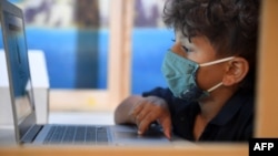 Seorang siswa mengikuti pembelajaran jarak jauh dari meja yang dipisahkan dari yang lain dengan penghalang plastik di STAR Eco Station Tutoring & Enrichment Center di Culver City, California, 10 September 2020. 