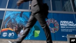 A delegate walks by an IMF banner, during the World Bank/IMF Annual Meetings at the International Monetary Fund (IMF) headquarters in Washington, Oct. 21, 2024. 