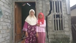 Marlina berfoto bersama anak perempuannya di depan bekas rumah mereka yang rusak akibat gempa bumi 2018 di desa Soulowe, Kecamatan Dolo, Kabupaten Sigi, Sulawesi Tengah (22/12/19) (VOA/Yoanes Litha).
