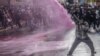 A protester reacts as Kenyan police officers spray water to disperse the crowd during a demonstration against tax increases in downtown Nairoibi on June 20, 2024.