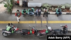 Pengemudi layanan ojek Gojek dan Grab enunggu penumpang di Jakarta pada 24 Juni 2020. (Foto: AFP/Adek Berry)