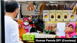 Seorang pedagang memperlihatkan surat tanda penerima bantuan kepada Presiden Jokowi yang lewat di depan lapaknya. (Foto: Courtesy/Humas Pemda Yogya)