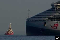 A ship belonging to the Open Arms aid group, left, one of the three ships loaded with canned food destined for Gaza, sails from the Cypriot port as a French warship is seen at the right, in Larnaca, Cyprus, on March 30, 2024.