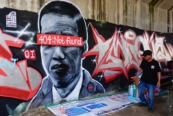 Sebuah mural yang menggambarkan Presiden Indonesia Joko Widodo dengan pesan kesalahan jaringan "404: tidak ditemukan" menutupi matanya, di Tangerang, Banten, sebelum dihapus dan polisi melakukan penyelidikan terkait hal tersebut. (Foto: AFP/Fajrin Rahardj