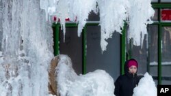 A woman passes an ice-covered fountain in New York's Bryant Park, Jan. 5, 2018. Frigid temperatures, some that could feel as cold as minus 30 degrees, moved across the East Coast on Friday as the region attempted to clean up from a massive winter storm. 