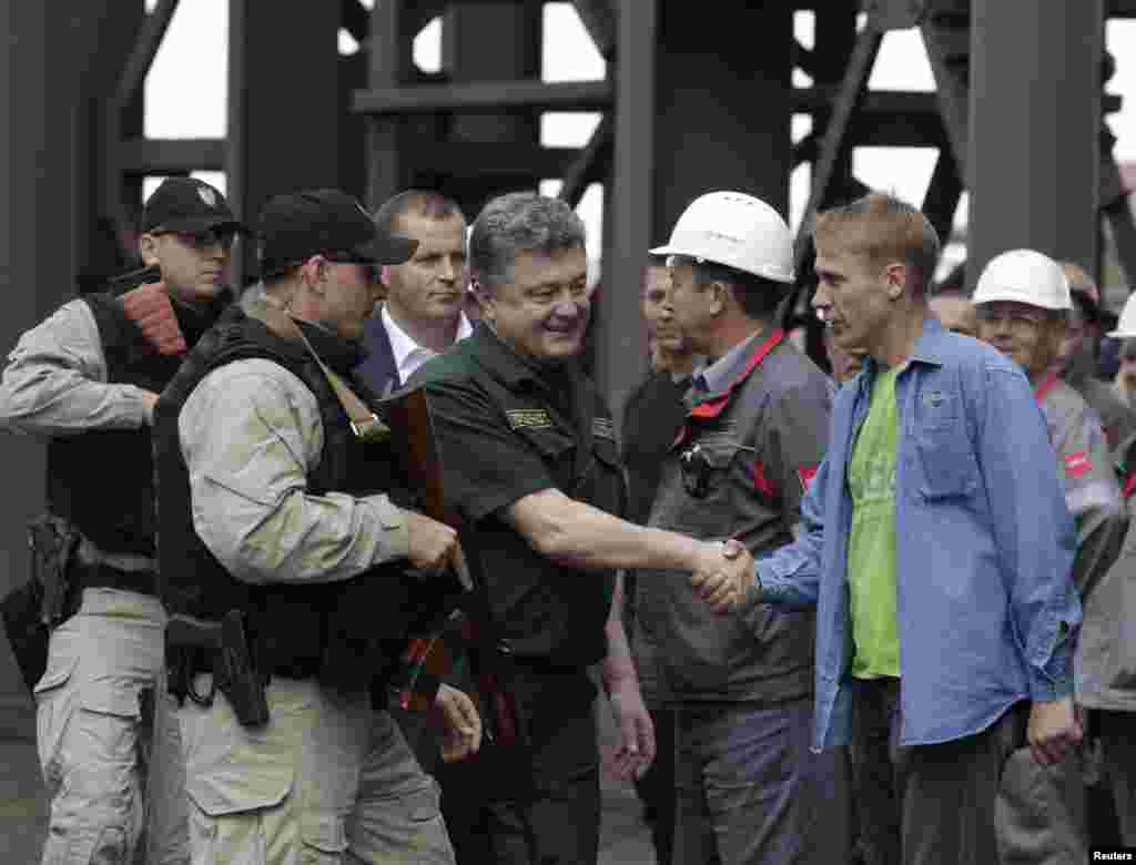 Ukrainian President Petro Poroshenko (C) shakes hands with a worker during his visit to the Ilyich Iron and Steel Works in the south-eastern port city of Mariupol September 8, 2014.