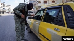Pripadnik Sirijskih bezbednosnih snaga proverava ličnu kartu građanina Latakije (Foto: Reuters/Karam al-Masri)