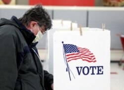 FILE - Voter Fred Hoffman fills out his ballot during the primary election in Ottawa, Illinois, March 17, 2020. The polling station was relocated from a nursing home to a former supermarket due to concerns over the outbreak of coronavirus.