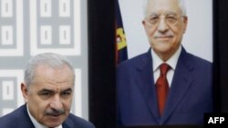 Perdana Menteri Palestina Mohammad Shtayyeh berdiri di samping potret Presiden Otoritas Palestina Mahmud Abbas selama rapat kabinet di mana ia mengumumkan pengunduran diri pemerintahannya dan menyerukan "langkah-langkah politik baru" di Ramallah. (Foto: AFP)