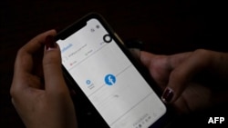 一名妇女使用手机在仰光查看Facebook，缅甸将军在夺权数天后下令互联网提供商限制访问Facebook。（2021年2月4日） （STR /法新社） 