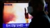 Seorang pria melintas di depan layar TV di Seoul, Korea Selatan, yang menyiarkan berita Korea Utara menembakkan proyektil, Senin, 9 Maret 2020. (Foto: Reuters)