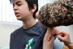 Seorang anak remaja diberi suntikan vaksin MMR di sekolah di Swansea, Wales selatan, Inggris. (Reuters)