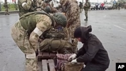 俄罗斯国防部2022年5月19日公布的视频截图显示俄罗斯军人在乌东顿涅茨克亲俄政权控制区检查离开马里乌波尔亚速钢铁厂的乌克兰军人的随身物品。