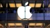 Seorang pelanggan berdiri di bawah logo Apple yang menyala saat dia melihat ke luar jendela toko Apple yang terletak di pusat kota Sydney. (Foto: Reuters)