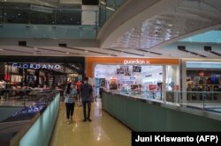Para pengunjung di sebuah mal yang tampak lengang di tengah penerapan PPKM untuk menahan penyebaran virus corona, di Surabaya, 10 Agustus, 2021. (Foto: Juni Kriswanto/AFP)