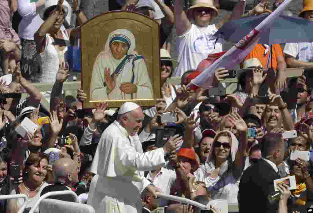 Pope Francis passes in front a portrait of Mother Teresa as he is driven through the crowd at the end of a canonization ceremony in St. Peter&#39;s Square at the Vatican, Sept. 4, 2016.
