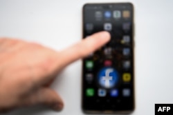 Media sosial online AS dan logo layanan jejaring sosial Facebook tampak pada layar smartphone. (Foto: AFP/Kirill KUDRYAVTSEV)