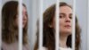 FILE - Belarusian journalists Katsiaryna Andreyeva and Darya Chultsova stand inside a defendants' cage during a court hearing in Minsk, Belarus, Feb. 18, 2021.