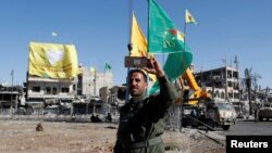 A fighter of Syrian Democratic Forces takes a selfie at Naim Roundabout in Raqqa, Syria, Oct. 18, 2017.