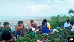 Wasu jama'a da ke kyautata zaton 'yan kabilar Rohingya ne yayin da wani kwalekwale ya sauke su a gabar ruwan kasar Malaysia
