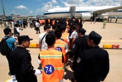 File - Chinese citizens who have been arrested over an alleged internet scam line up before a deporting back to China, at the international airport in Phnom Penh, Cambodia, Thursday, Oct. 12, 2017.