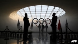 在保安的注视下,北京冬奥会工作人员在奥运塔内为奥林匹克圣火添加燃料。