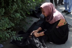 An Afghan woman tries to identify a body at a hospital in Kabul, Afghanistan, Aug. 27, 2021, a day after a deadly attack outside the airport.