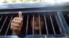 FILE - Myanmar activist Moe Thway gives a thumbs-up sign from a police truck as he is taken to a township court with other activists, in Yangon, Myanmar, Nov 22, 2013.
