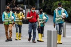 Para pekerja migran di layanan-layanan penting menyeberang sebuah jalan di kawasan Orchard Road di tengah wabah virus corona di Singapura, 27 Mei 2020. (Foto: Reuters)