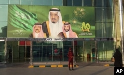 FILE - Images of King Salman, center, Crown Prince Mohammed bin Nayef, left, and Deputy Crown Prince Mohammed bin Salman hang at the entrance of a shopping center in Riyadh, Saudi Arabia, Dec. 14, 2015.