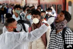 Seorang petugas kesehatan mengumpulkan sampel swab dari seorang pelancong di stasiun kereta api untuk menguji COVID-19 sebelum mengizinkannya memasuki kota itu, di Mumbai, India, Rabu, 12 Januari 2022. (Foto: AP)