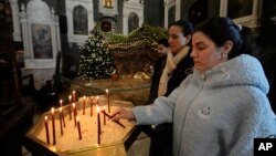 A Syrian Christian woman lights a candle during the first Sunday Mass since Syrian President Bashar al-Assad's ouster, at Mariamiya Orthodox Church in Old Damascus, Syria, Dec. 15, 2024.