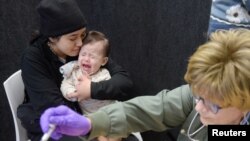 Devonay Pena menghibur putrinya yang berusia 13 bulan, Jaqi Herrera, setelah Herrera menerima dosis pertama vaksin MMR di Departemen Kesehatan Kota Lubbock di Lubbock, Texas, AS, 27 Februari 2025. (Foto: Reuters)