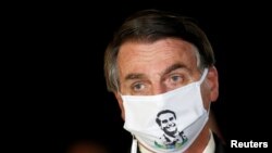 Presiden Brasil Jair Bolsonaro berbicara dengan wartawan sambil mengenakan masker pelindung saat tiba di Istana Alvorada, di tengah wabah penyakit virus korona, di Brasilia, 22 Mei 2020. (Foto: Reuters)